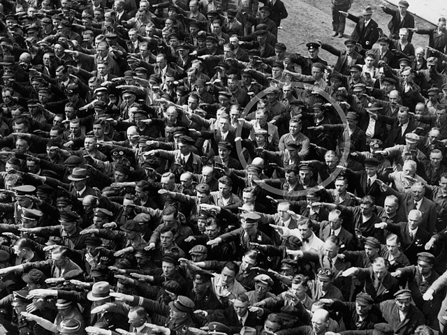 bilden visar en folkmassa från nazitiden där alla gör en  nazisthälsning utom en person som står med korsade armar