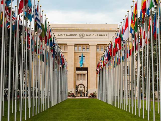 Bilden visar Förenta nationernas huvudkontor med flaggor från världens länder framför