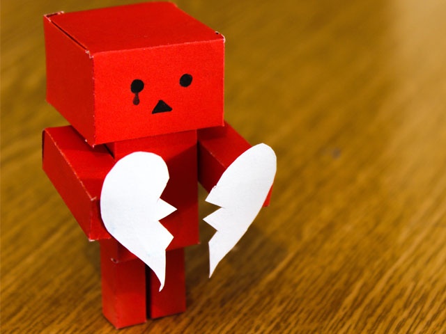 Bilden visar en rödfärgad robotfigur i papper som håller i ett vitt brustet hjärta