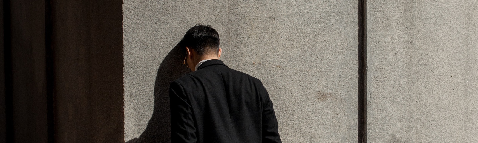 Bilden visar en svartklädd person som står med huvudet mot en vägg