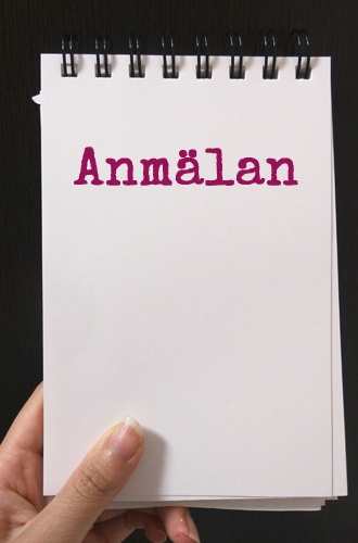 Bilde visar en hand som håller i ett pappersblock där det står "anmälan" med lila bokstäver