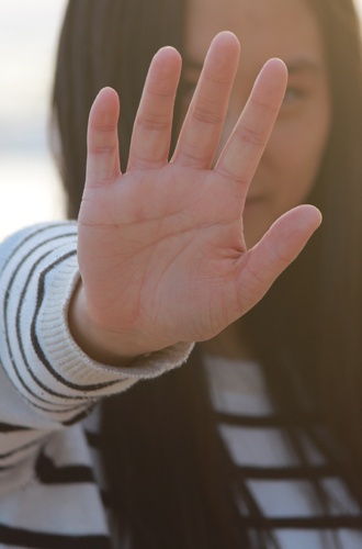 Person håller upp handen som för att säga stopp eller att hen är anti något